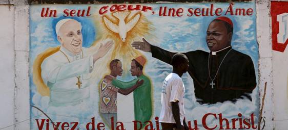  Bangui, un homme passe devant une fresque murale mettant en scne le pape Franois et l'archevque de Bangui, Dieudonn Nzapalainga. Au centre, lan de fraternit entre un musulman et un chrtien.